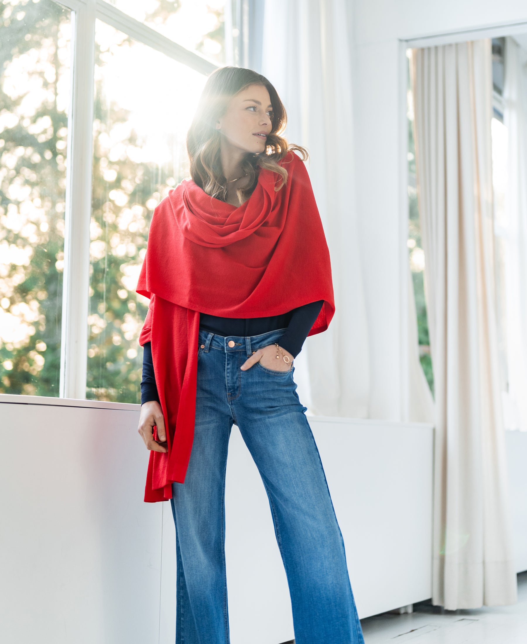 PLEIN PUBLIQUE Merino wool wrap LA BELLA in coral red, shown with sunlight streaming behind.