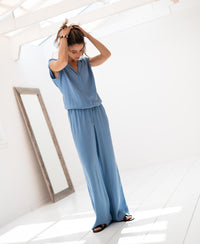 Woman wearing blue LA LYNETTE jeans, standing by a mirror indoors.