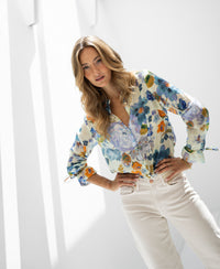Light blue floral blouse from Plein Publique La Binocle displayed in a sunlit room.