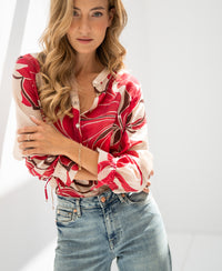 Woman wearing a red printed blouse by Plein Publique in natural light.