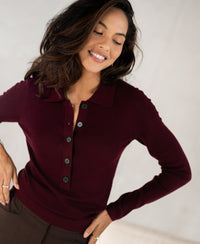 Woman wearing a Bordeaux merino wool polo shirt, smiling with eyes closed.
