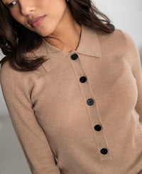 Soft camel merino wool polo with black buttons and collar, softly lit.