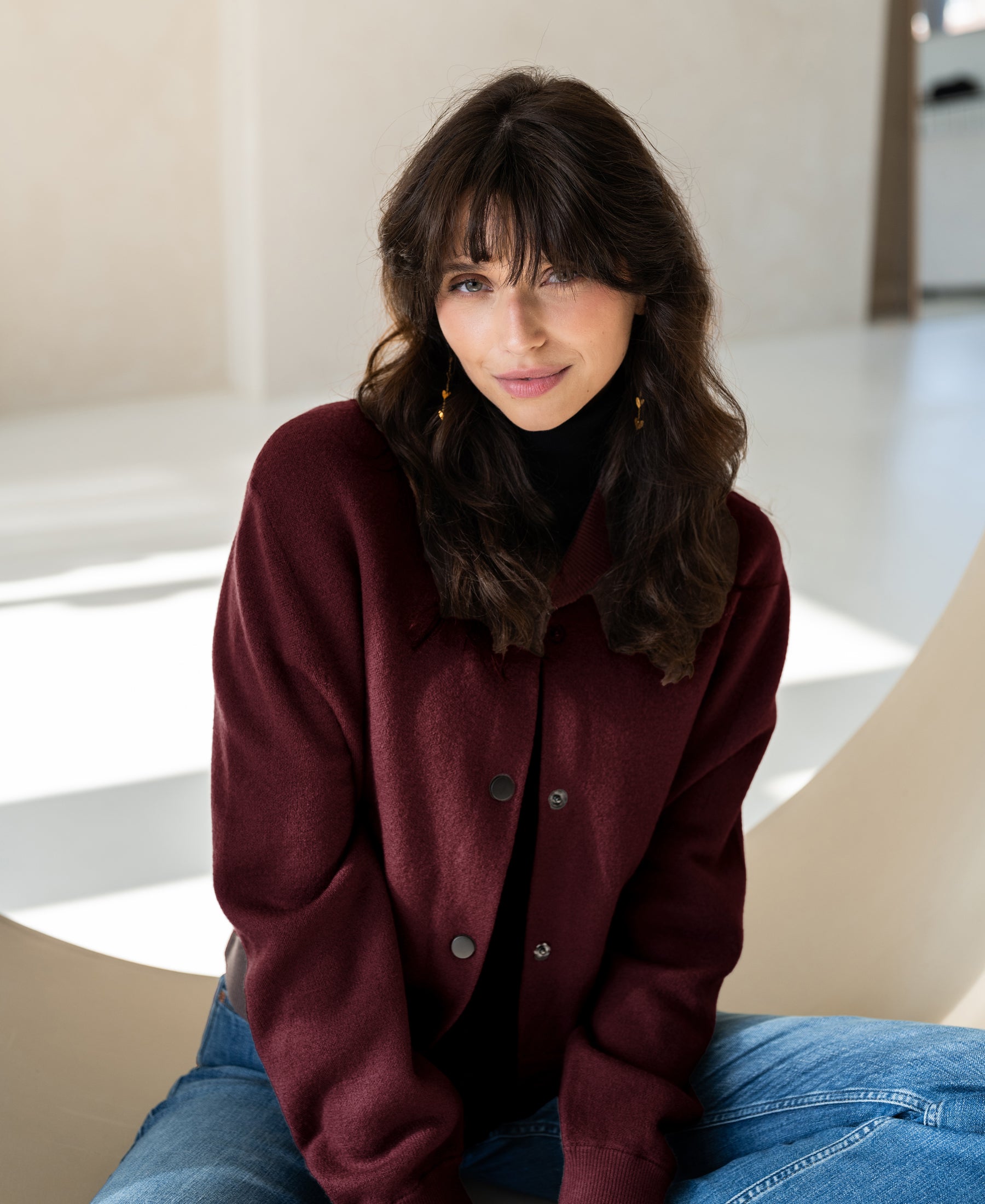 A woman wears a red PLEIN PUBLIQUE LA BOMBA bomber jacket.