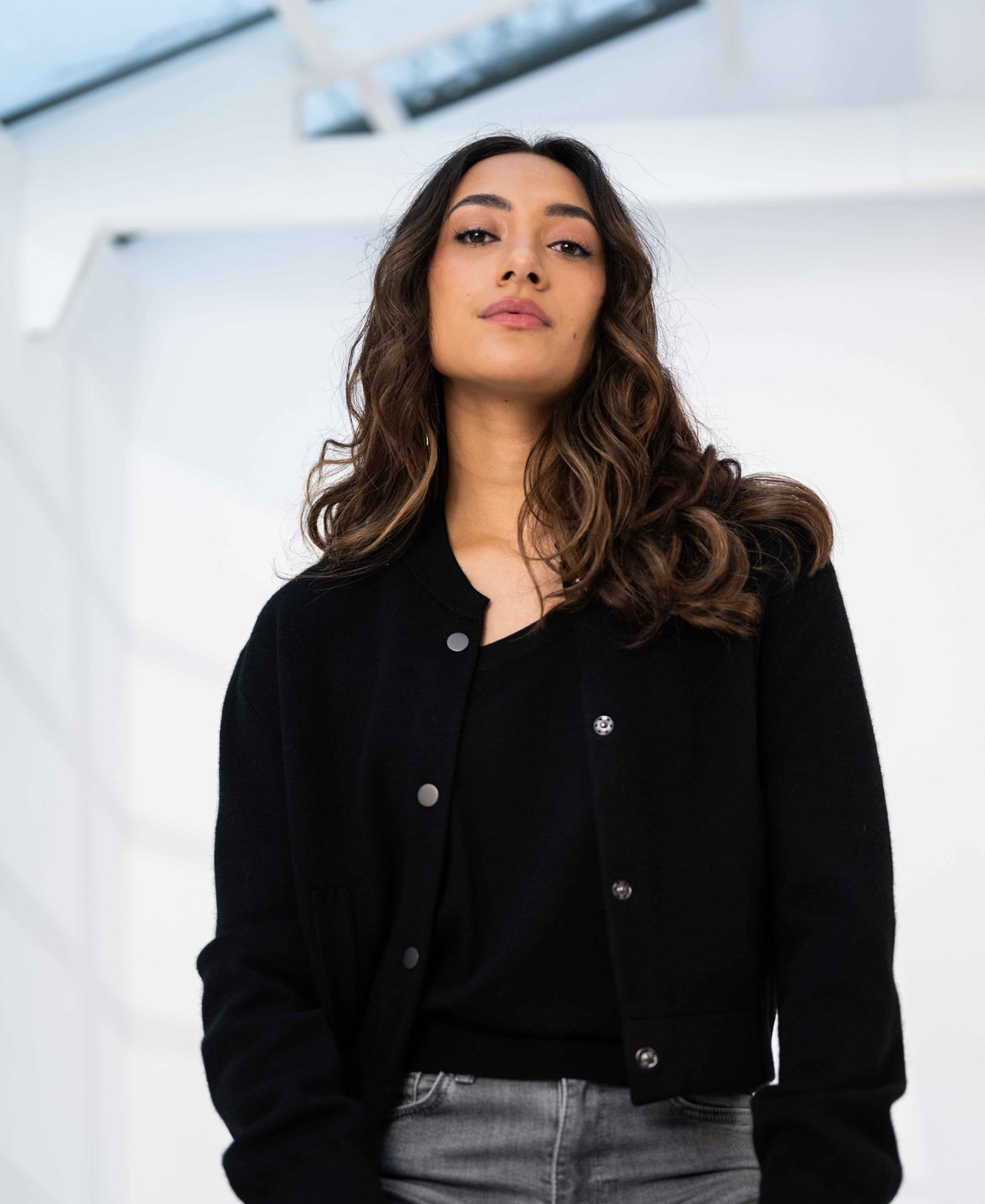 Black PLEIN PUBLIQUE LA BOMBA bomber jacket shown in a modern setting.