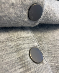 Close-up of two black buttons on soft, light gray melange bomber jacket by PLEIN PUBLIQUE.