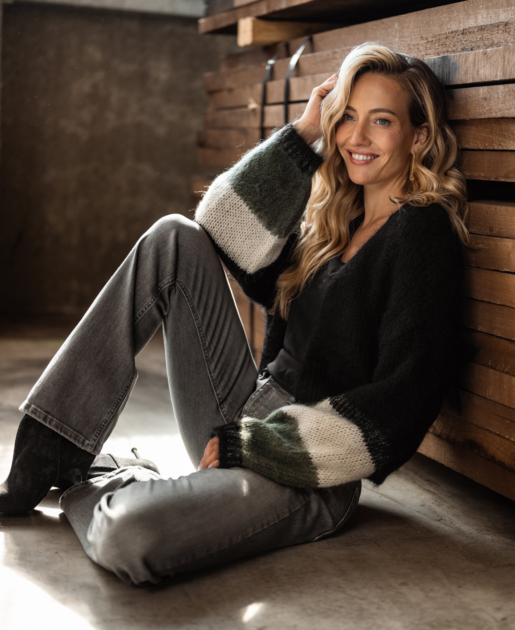 Black striped fluffy vest by PLEIN PUBLIQUE shown in front of stacked wooden planks.
