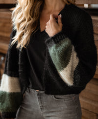 Fluffy black PLEIN PUBLIQUE vest with stripes and green-white sleeves, shown indoors.