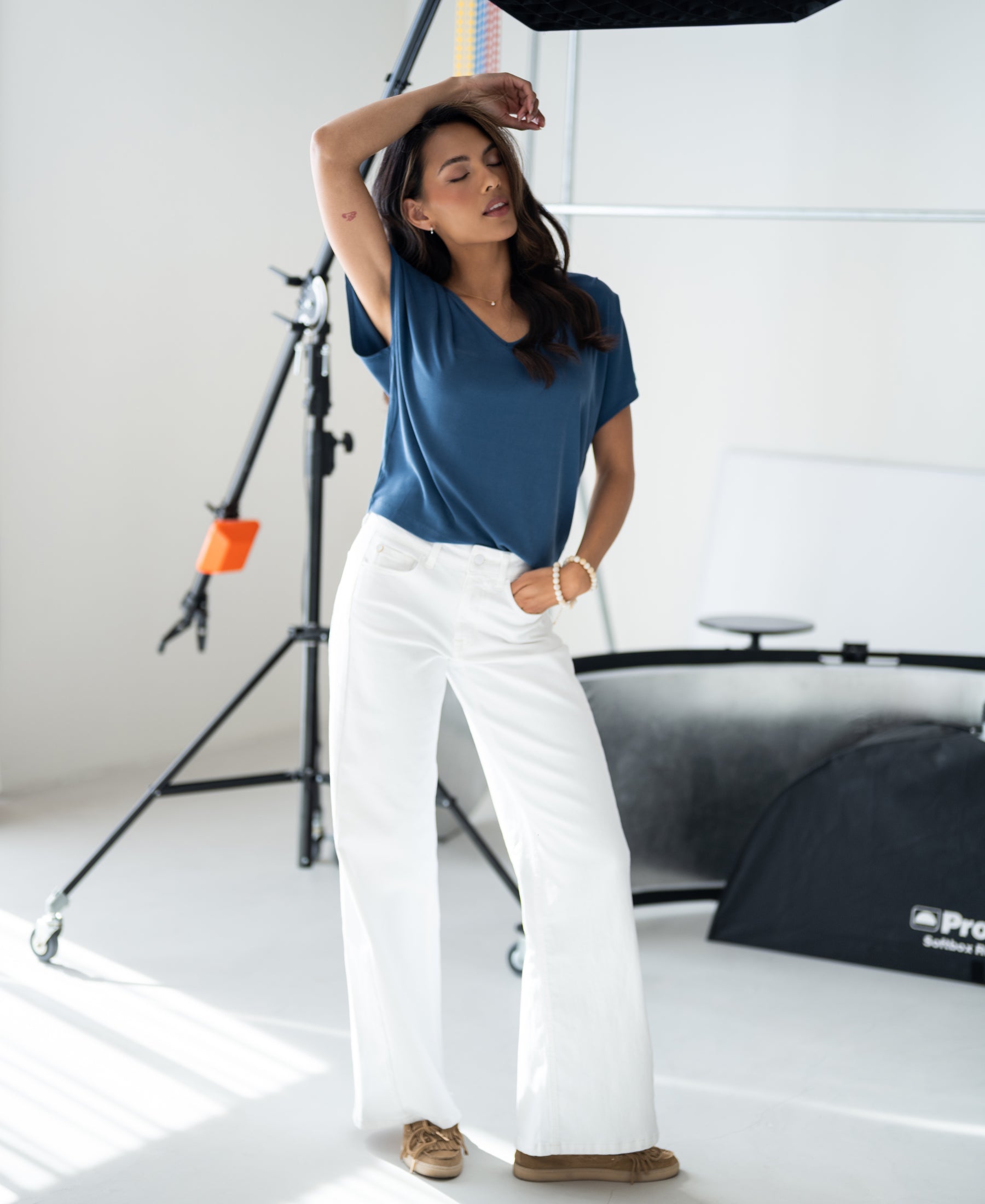 Model wears a blue ribbed T-shirt by Plein Publique in a bright studio with photography equipment.