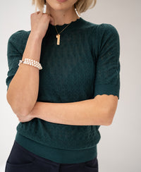 Woman wearing LA BRIOCHE Merino sweater from PLEIN PUBLIQUE, arms crossed.