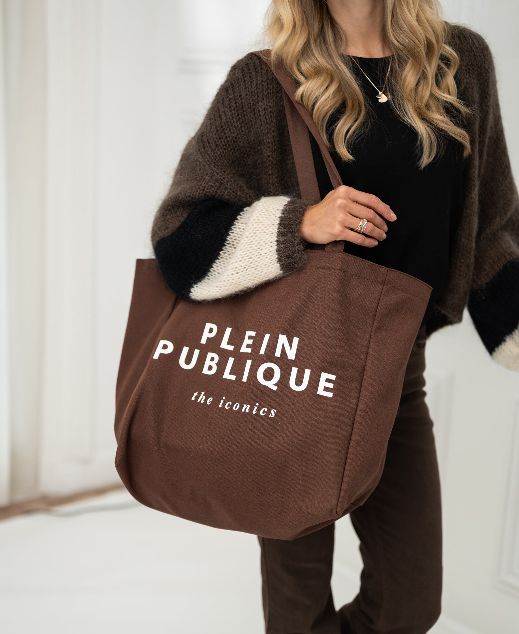 Brown canvas tote bag by PLEIN PUBLIQUE, called "The Bag," shown being held.