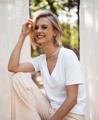 White V-neck T-shirt LA VIDA by PLEIN PUBLIQUE, shown outdoors among sheer curtains.