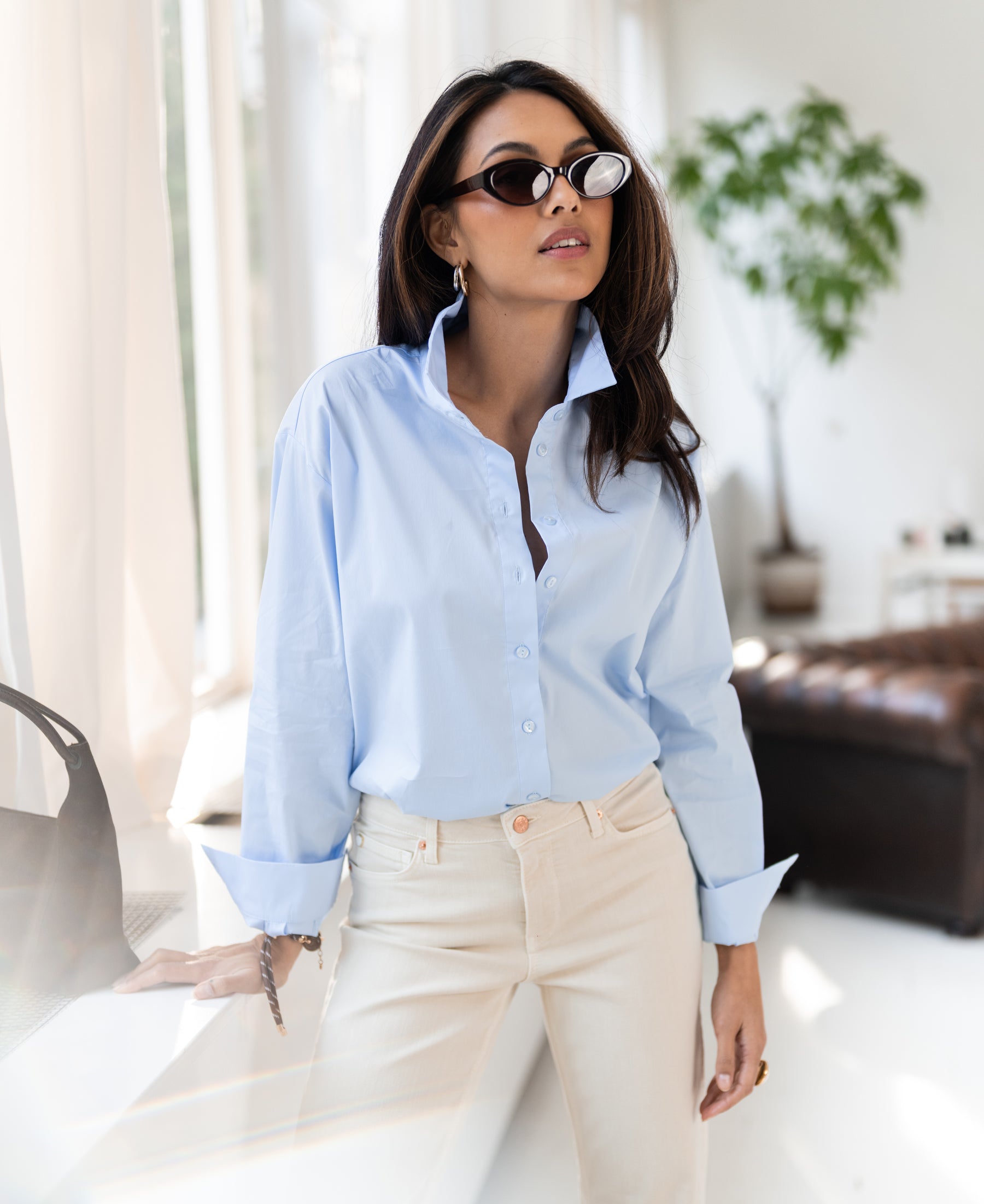 Oversized easy-iron light blue blouse shown indoors.