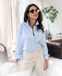 Oversized easy-iron light blue blouse shown indoors.