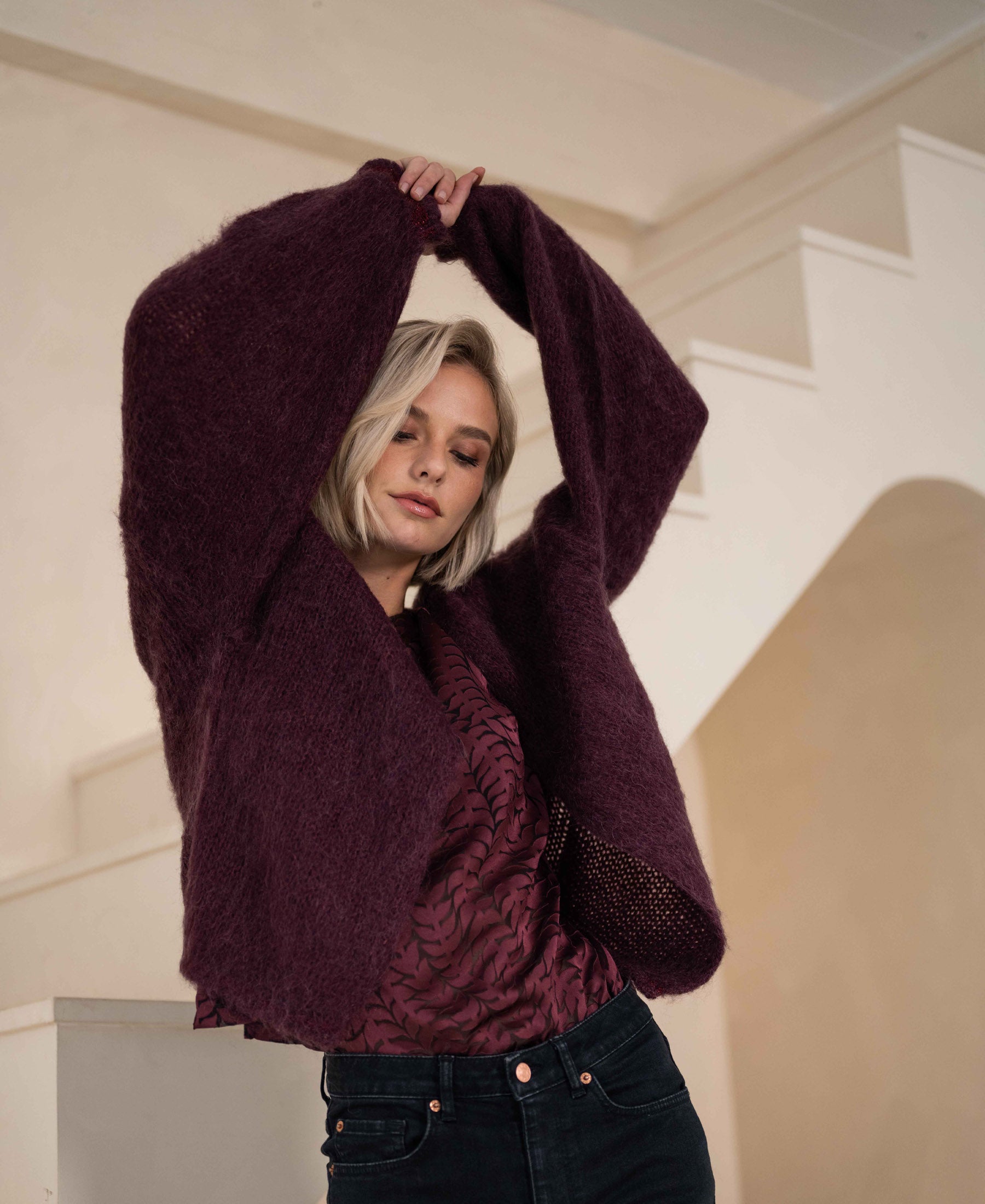 Burgundy fluffy vest made of soft material, shown indoors.