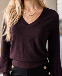 Woman wearing PLEIN PUBLIQUE Merino wool V-neck sweater in Bordeaux, shown from shoulders to waist.