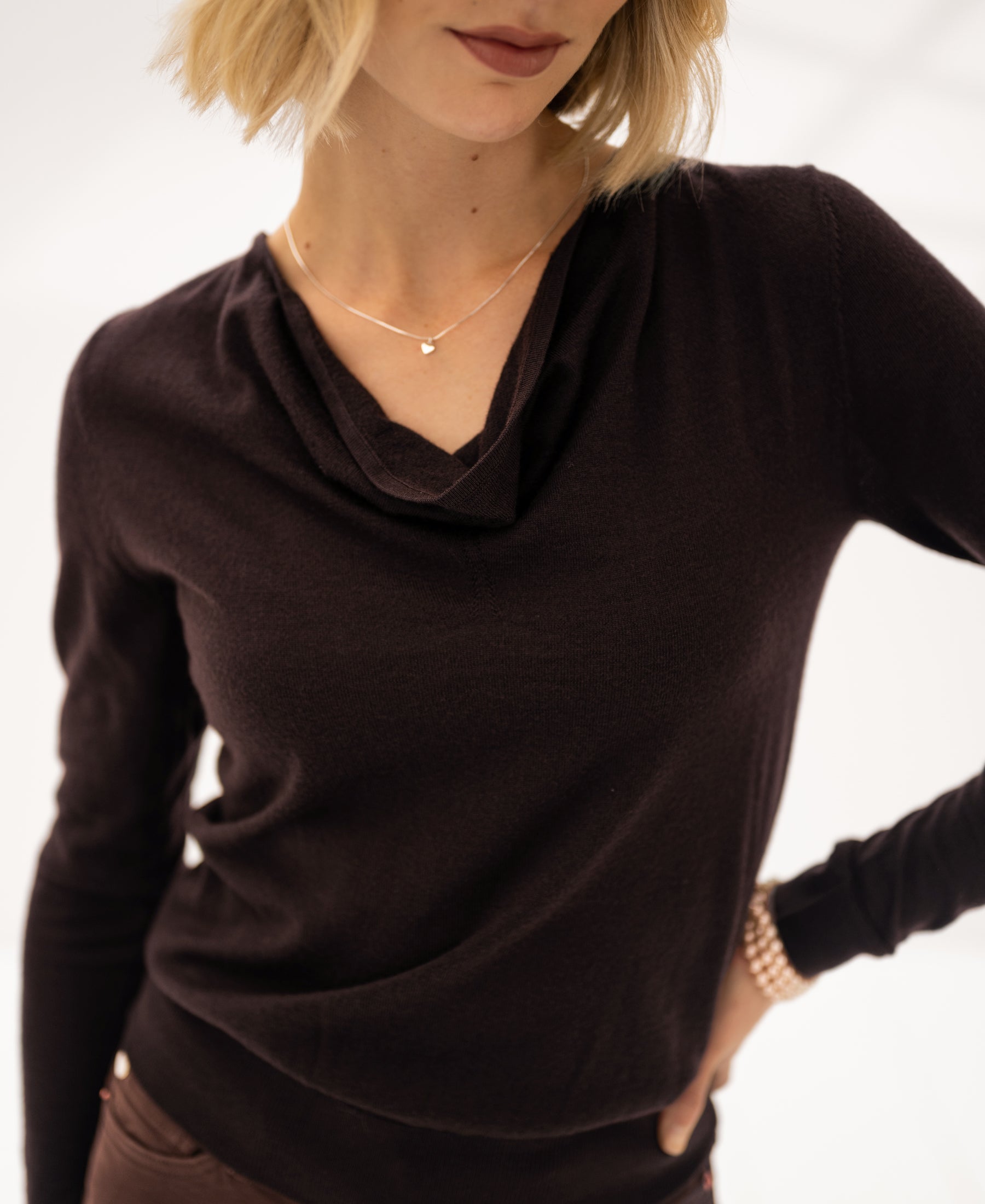Chocolate brown LA CASCADE sweater with waterfall neckline, shown partly, model's face partially out of frame.