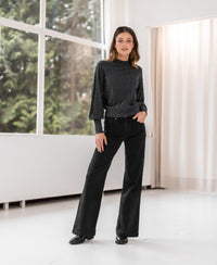 Woman indoors by large windows wearing the Plein Publique beaded charcoal turtleneck sweater.