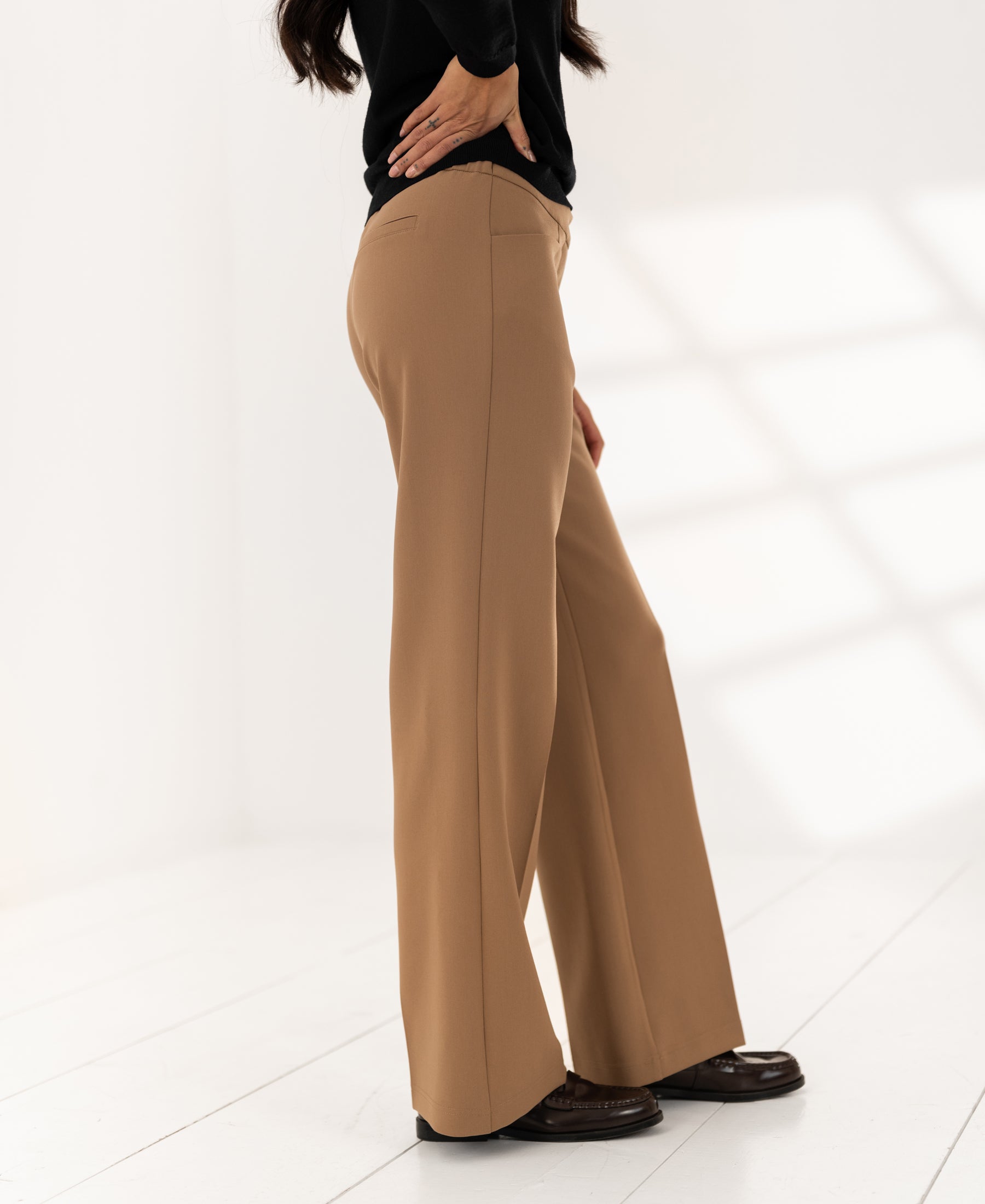 Wide-leg camel pants in a bright, minimalist room.