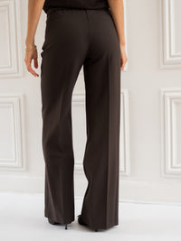 Wide-leg brown pants in choco color shown from the back indoors.