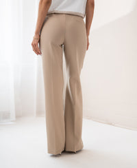 Wide-leg light sand trousers from PLEIN PUBLIQUE shown in a bright indoor setting.