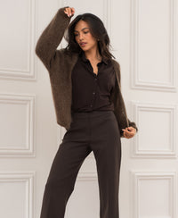 Woman wearing wide leg LE CENTRE Pure Choco trousers against a white wall.