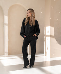 Black pinstripe vest in a bright, minimal room with arched niches.