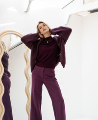 Bordeaux turtleneck sweater by PLEIN PUBLIQUE displayed near a wavy mirror in a bright, white room.