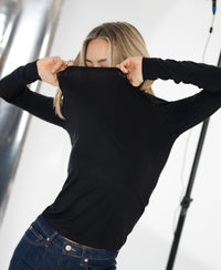 Black LE CHOLET Luxe undershirt by PLEIN PUBLIQUE, collar pulled up, shown against a blurred background.