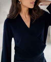 Woman wearing a PLEIN PUBLIQUE navy blue wrap sweater, front view.