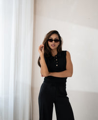 Sleeveless LE CLUB Black polo top from PLEIN PUBLIQUE shown by a woman posing confidently by a window.