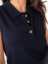 Close-up of sleeveless navy polo sweater, shown from shoulders down.