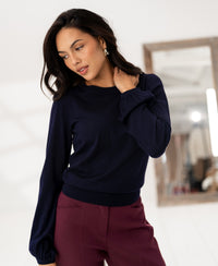 Woman wearing a PLEIN PUBLIQUE dark blue merino wool LA COEUR sweater.