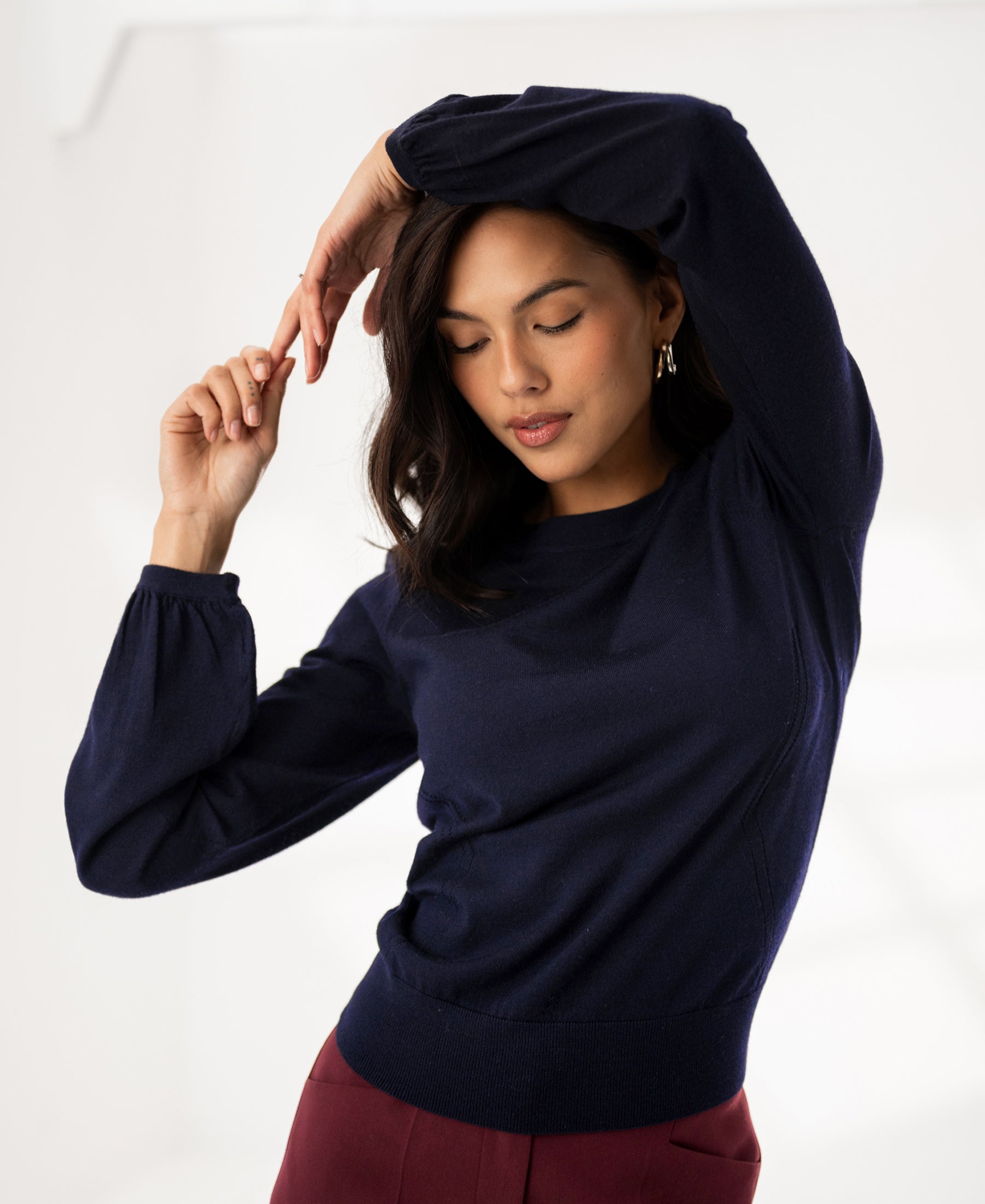 Woman wearing the LA COEUR merino wool sweater in dark blue by PLEIN PUBLIQUE, arm raised.