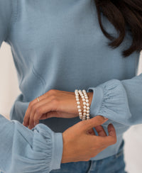 Woman wearing light blue LA COEUR Merino wool sweater by PLEIN PUBLIQUE, adjusting her sleeve.