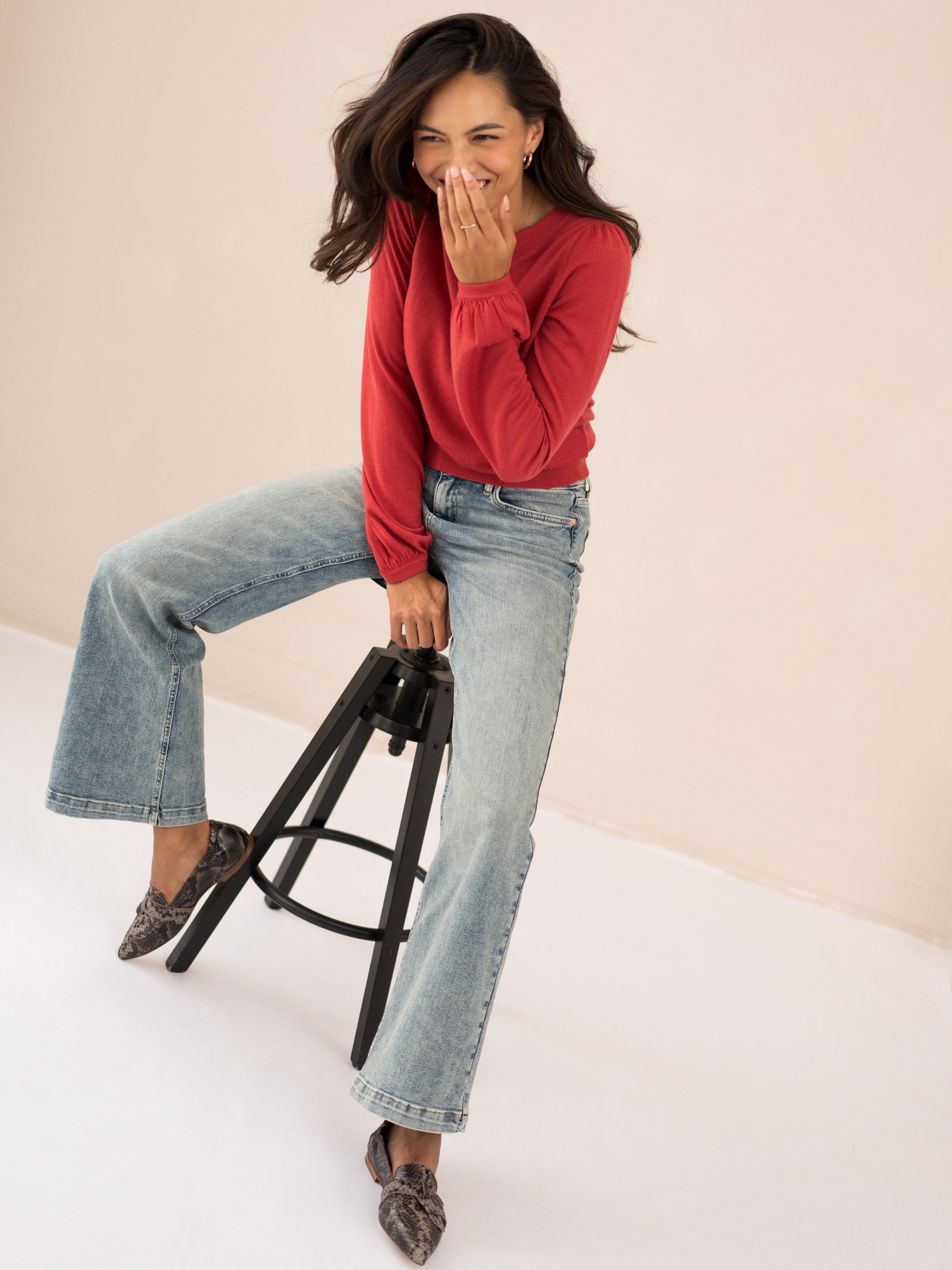 Red merino wool sweater with balloon sleeves, shown on a seated model looking down.
