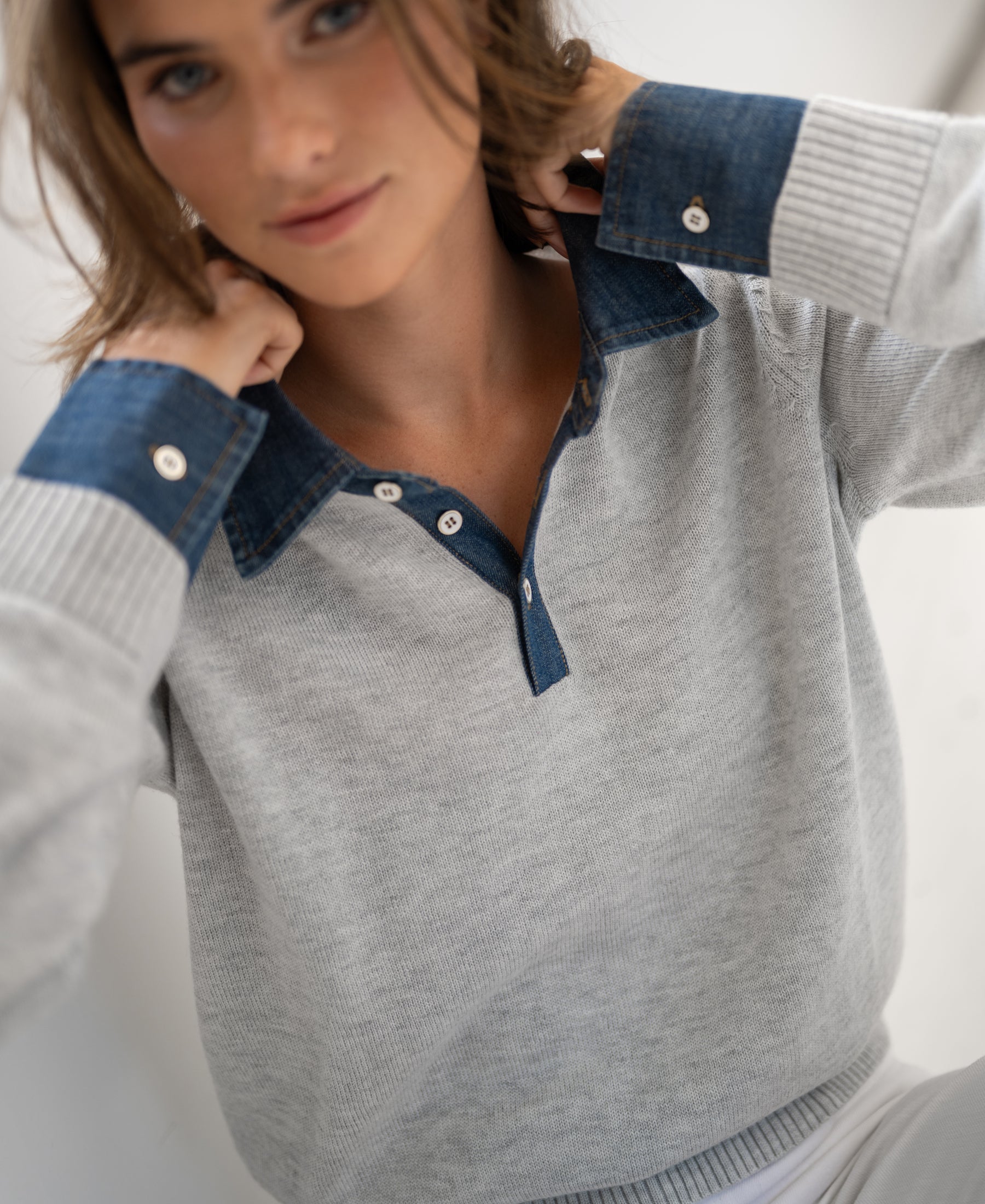 Light grey knit blouse by PLEIN PUBLIQUE, shown being adjusted.