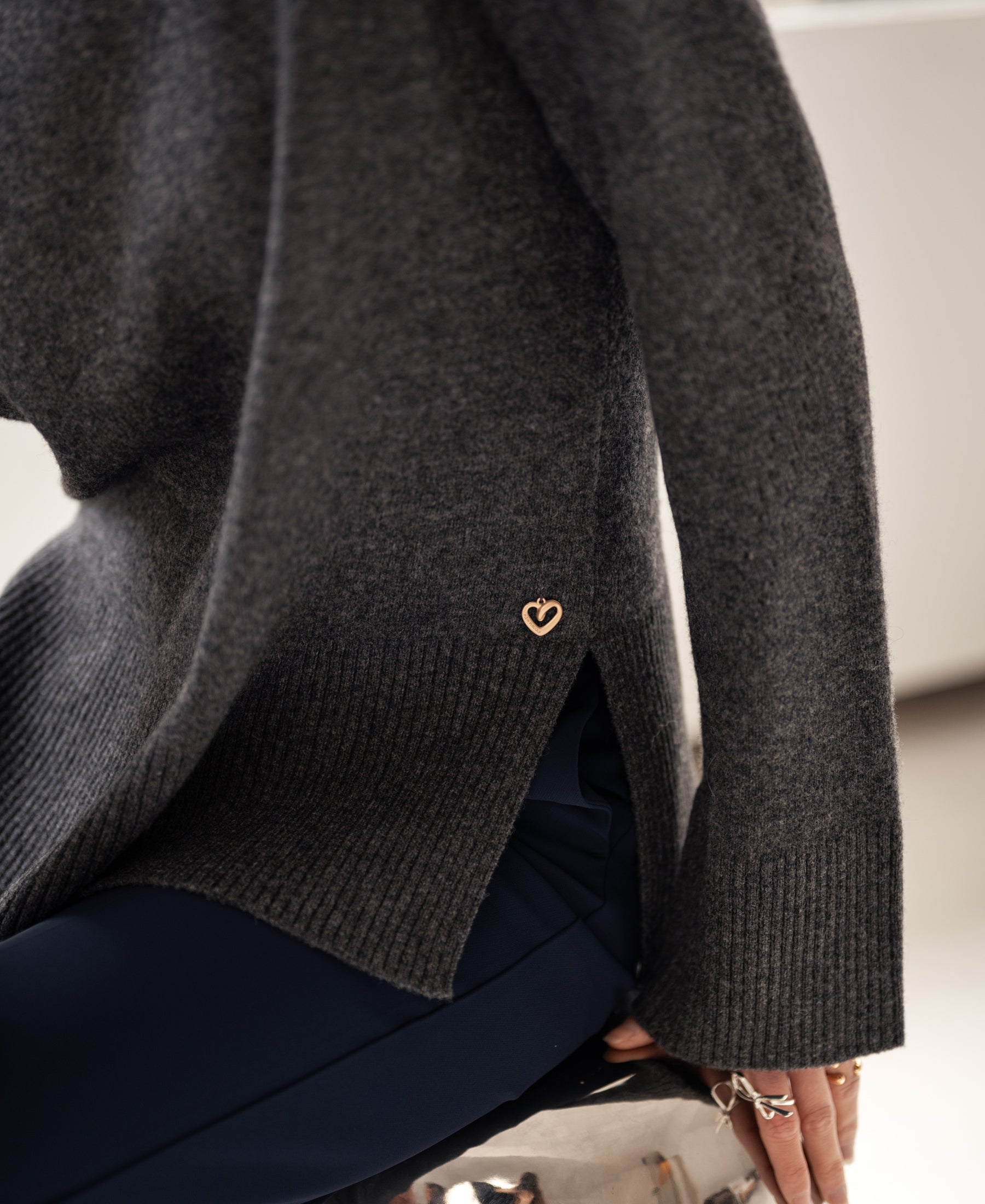 Charcoal turtleneck sweater with gold heart detail.