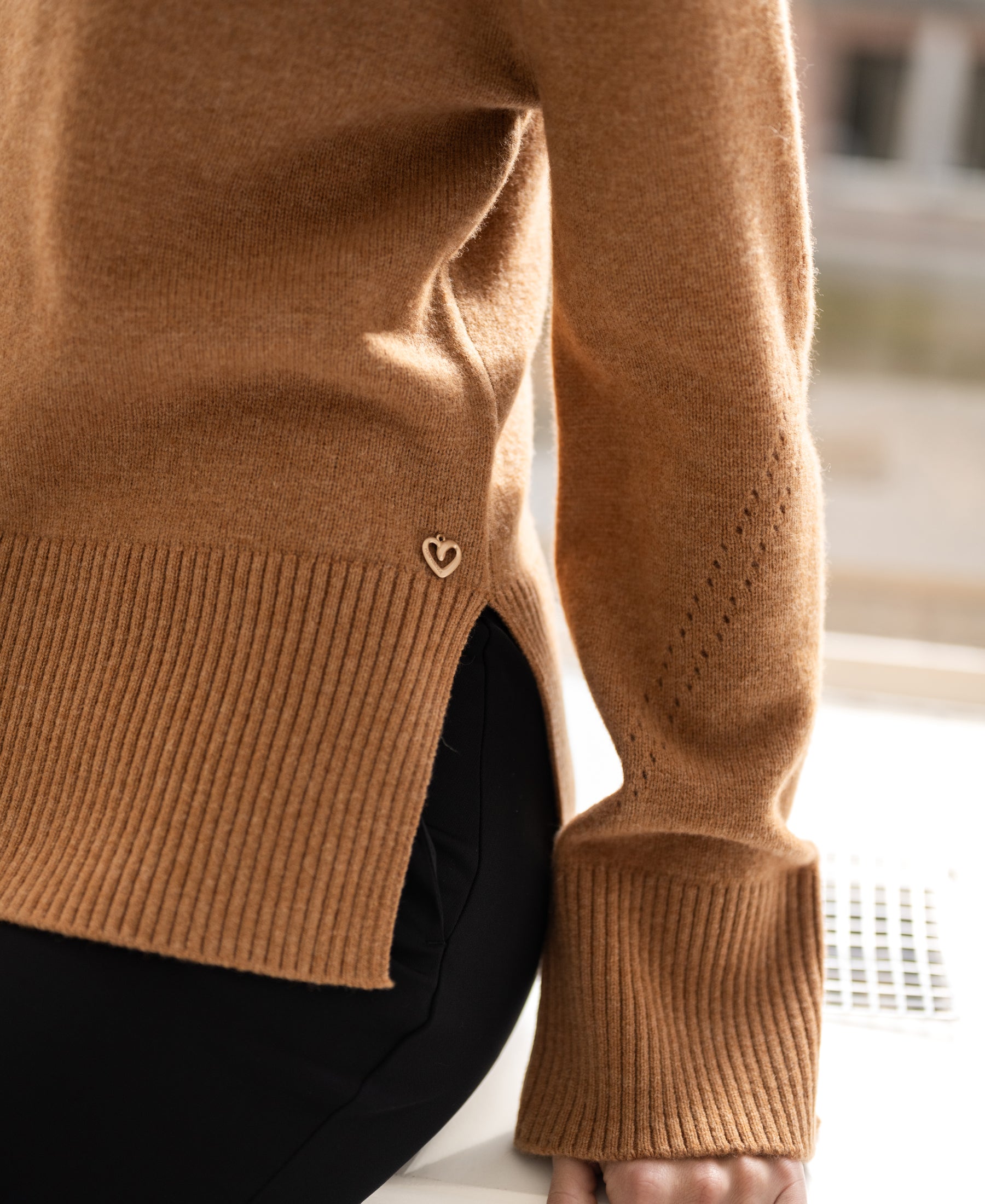 Camel ribbed turtleneck sweater with heart pin, shown from the front.