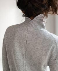 Back view of a person wearing a grey turtleneck sweater.