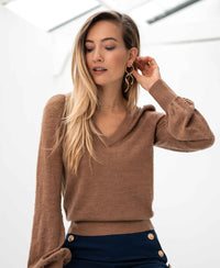 Woman wearing a PLEIN PUBLIQUE Merino wool V-neck sweater in chai tea color.