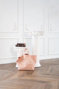 Blush canvas tote bag by Plein Publique displayed on white columns in an elegant, white-walled room.