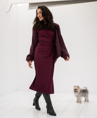 Woman wearing a Bordeaux LA Toulouse travel dress walks indoors, smiling.