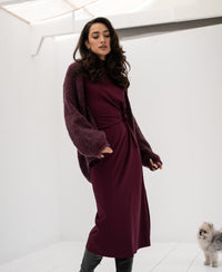 Woman wearing a Bordeaux LA TOULOUSE travel dress by OVERIG stands indoors.