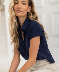 Dark blue PLEIN PUBLIQUE LA DELON travel blouse shown against white paneled walls.