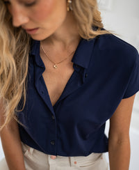 Woman wearing a PLEIN PUBLIQUE dark blue Travel Blouse LA DELON, looking down.