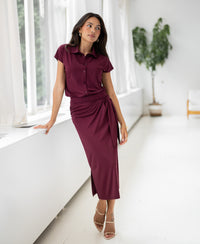 Travel skirt in wine red by PLEIN PUBLIQUE shown near a window in a bright, modern room.