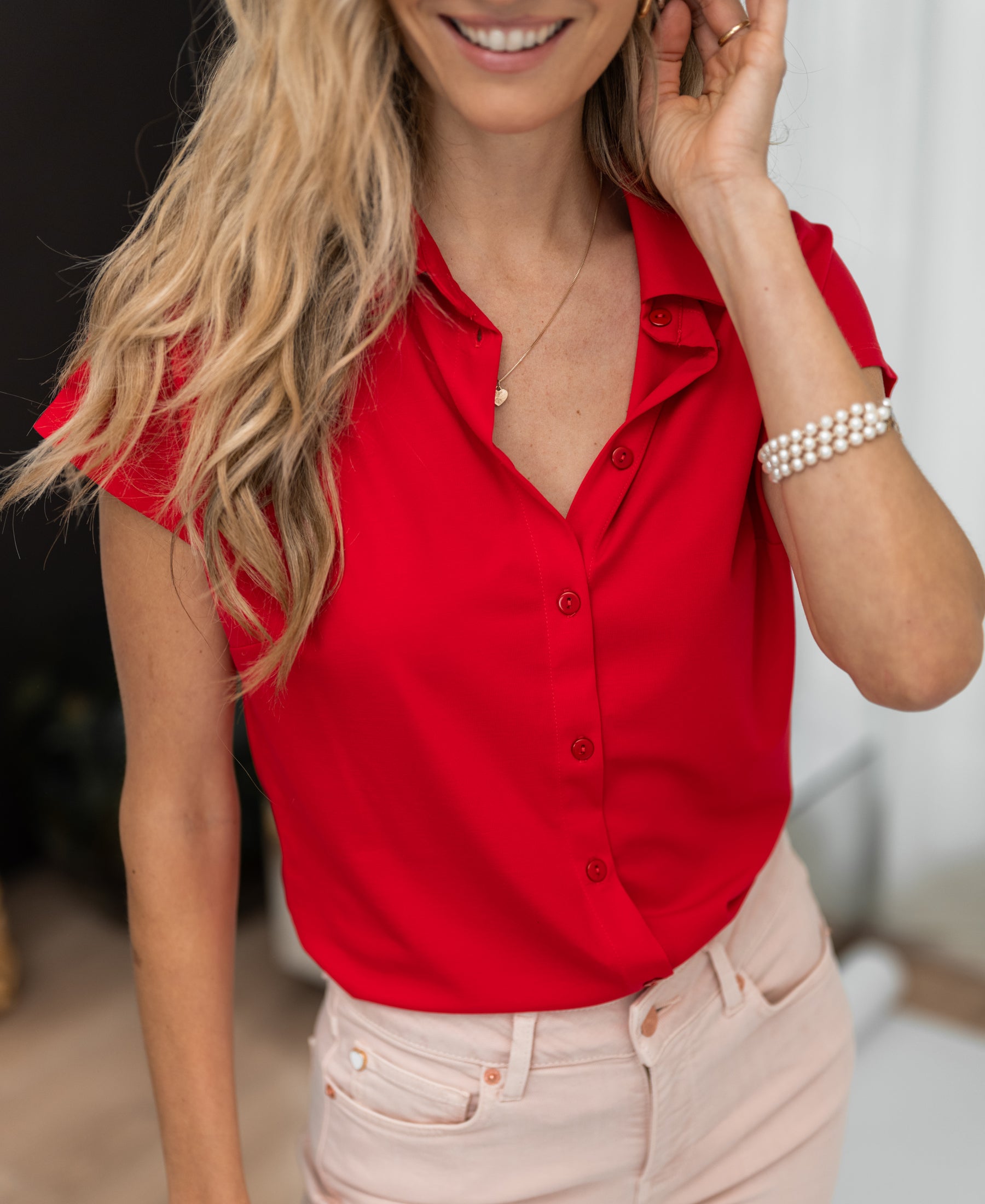 Red travel blouse by PLEIN PUBLIQUE, shown on a woman touching her hair.