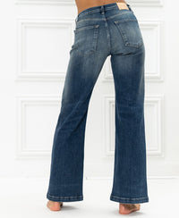 Back view of wide leg blue jeans by PLEIN PUBLIQUE, shown against a white paneled wall.