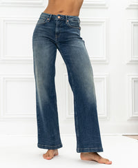 Wide leg blue vintage jeans by Plein Publique, shown against a white paneled wall.