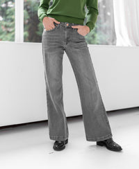 Wide leg jeans in grey stonewash, hands in pockets.